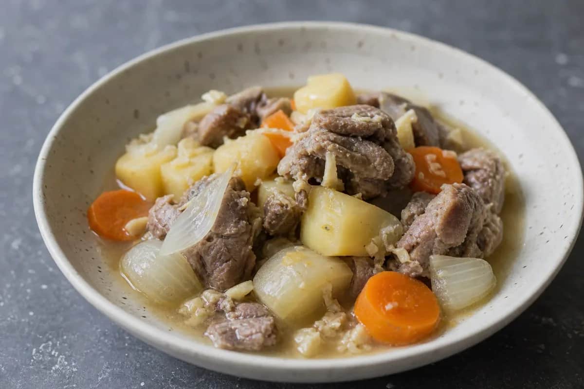 Plated Mongolian Chanasan Makh featuring tender boiled lamb and colorful root vegetables, garnished with herbs.