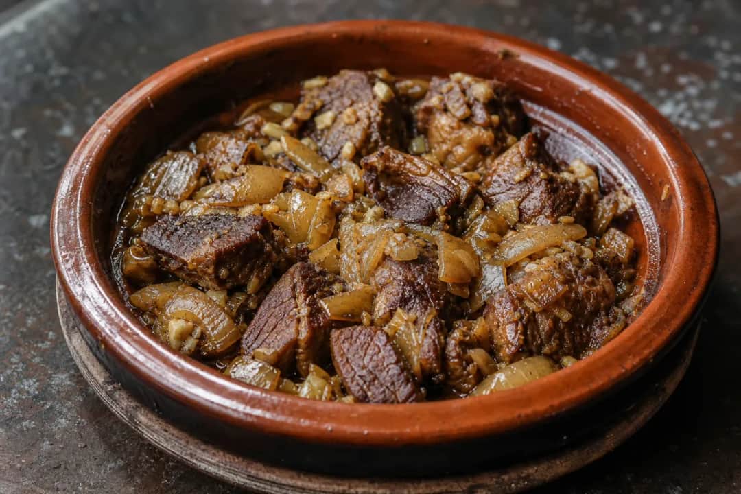 Tender lamb pieces in a rich sauce with prunes and almonds, garnished with herbs.