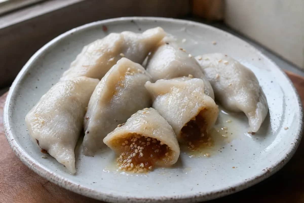 Steamed yomari dumplings filled with sweet chaku and sesame, garnished beautifully.