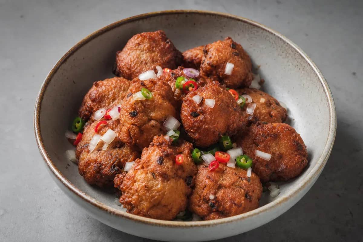 Golden brown Nigerian Akara fritters served on a plate with fresh chili garnish.