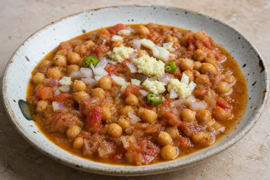 A hearty bowl of chana masala with chickpeas and spices, garnished with fresh cilantro.
