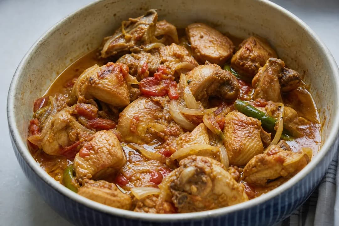 A vibrant plate of chicken karahi garnished with fresh green chilies and herbs, featuring tender chicken chunks and a rich tomato sauce.