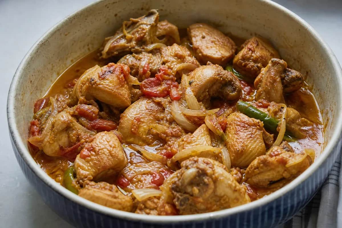 A vibrant plate of chicken karahi garnished with fresh green chilies and herbs, featuring tender chicken chunks and a rich tomato sauce.