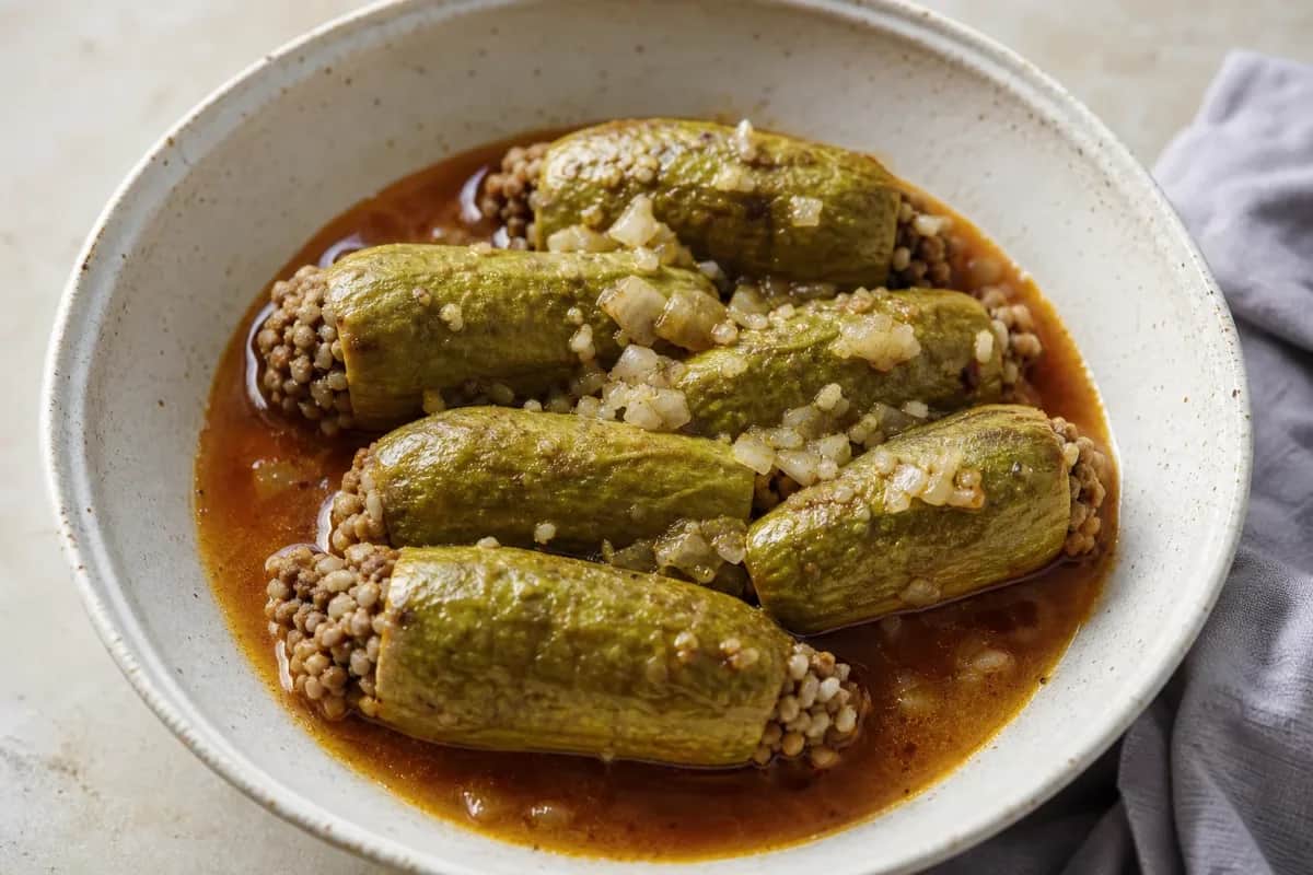 Stuffed zucchini in tomato broth, garnished with herbs, showcasing a vibrant color and savory texture.