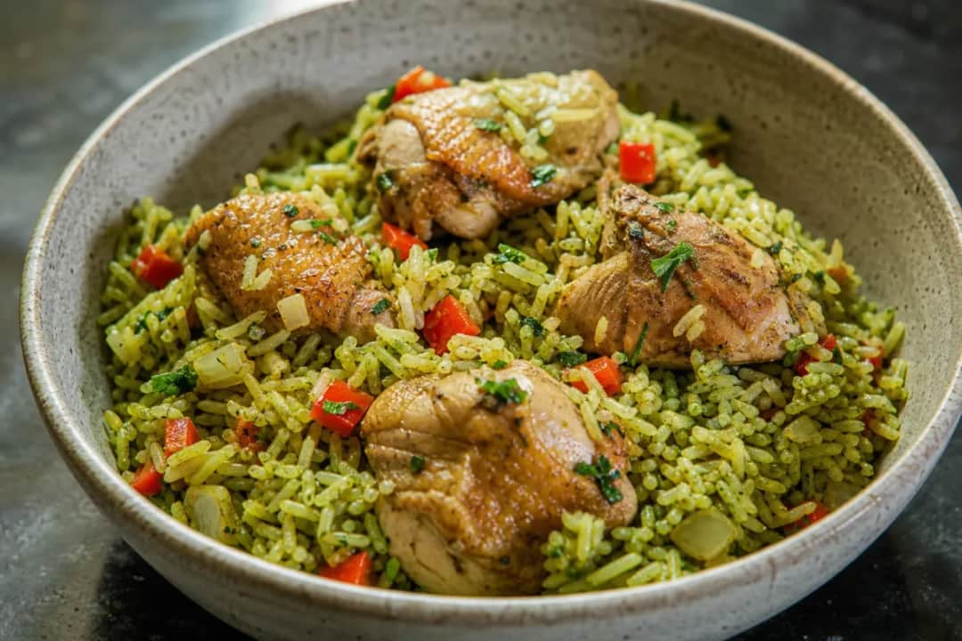 A colorful plate of Peruvian Arroz con Pollo garnished with cilantro, showcasing chicken, rice, and vibrant vegetables.