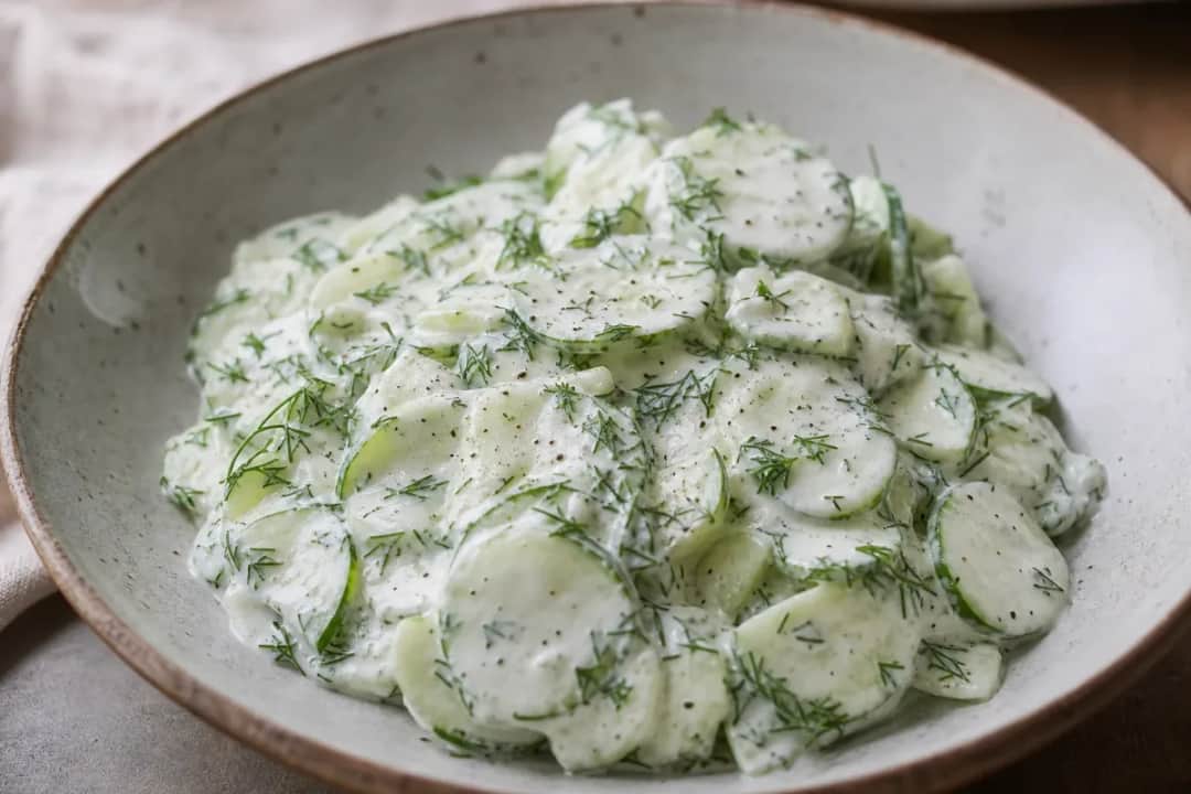 A creamy cucumber salad with fresh dill, garnished and served in a bowl, showcasing a vibrant green color and smooth texture.