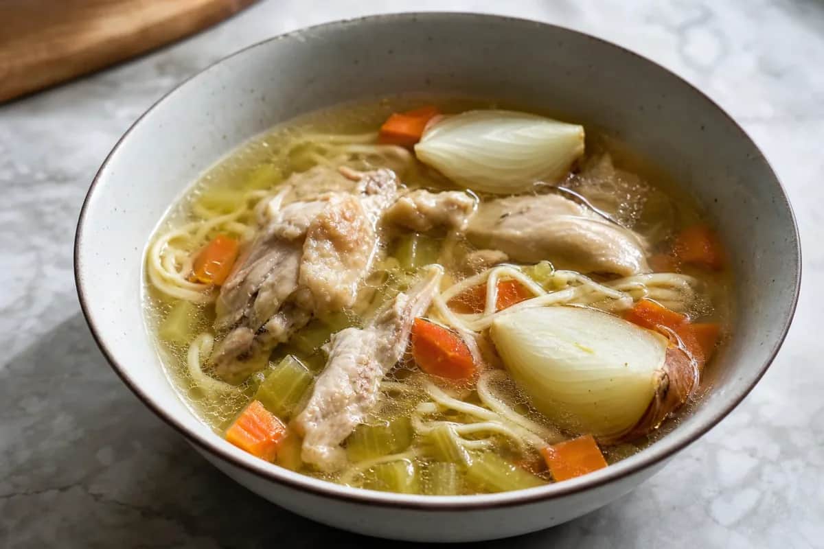 A bowl of Polish Rosół with golden chicken, delicate noodles, and vibrant fresh herbs.