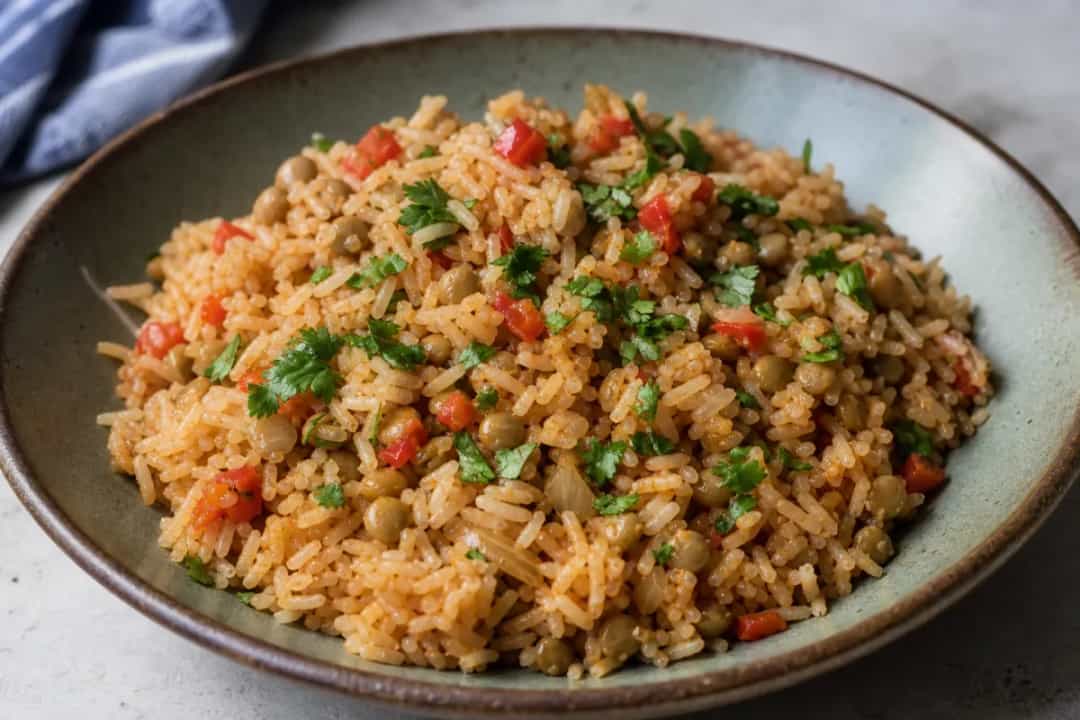 A vibrant plate of Puerto Rican Arroz con Gandules garnished with fresh herbs and served with a side of avocado.