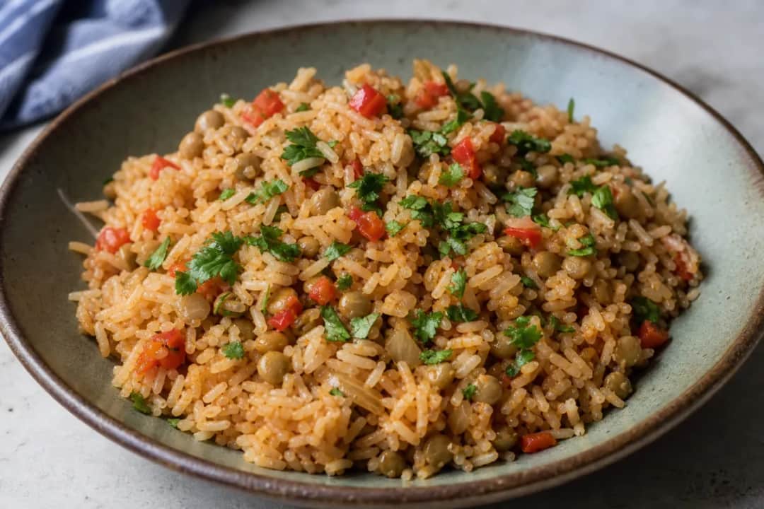 A vibrant plate of Puerto Rican Arroz con Gandules garnished with fresh herbs and served with a side of avocado.