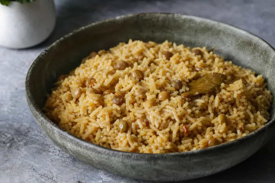 A vibrant plate of Arroz con Gandules, featuring fluffy rice, green pigeon peas, and colorful sofrito garnished with cilantro.