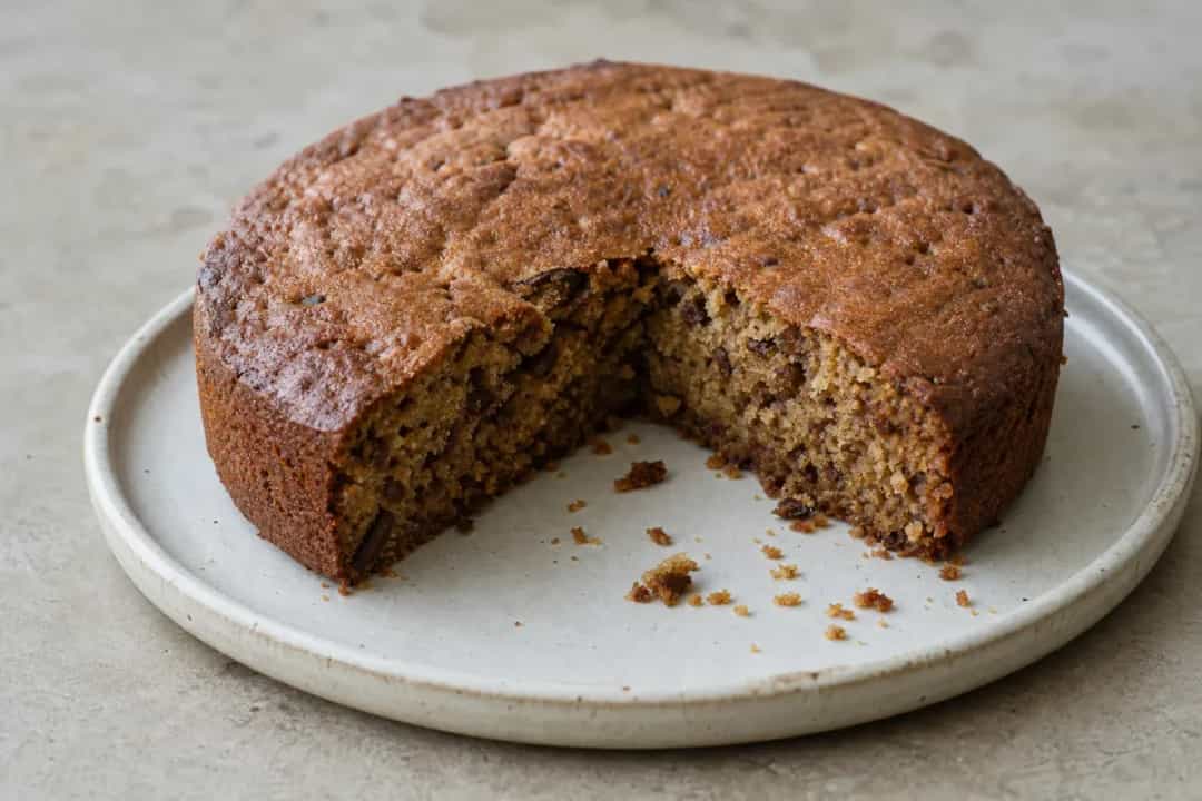 Moist Saudi date cake topped with tahini and cardamom, garnished beautifully.