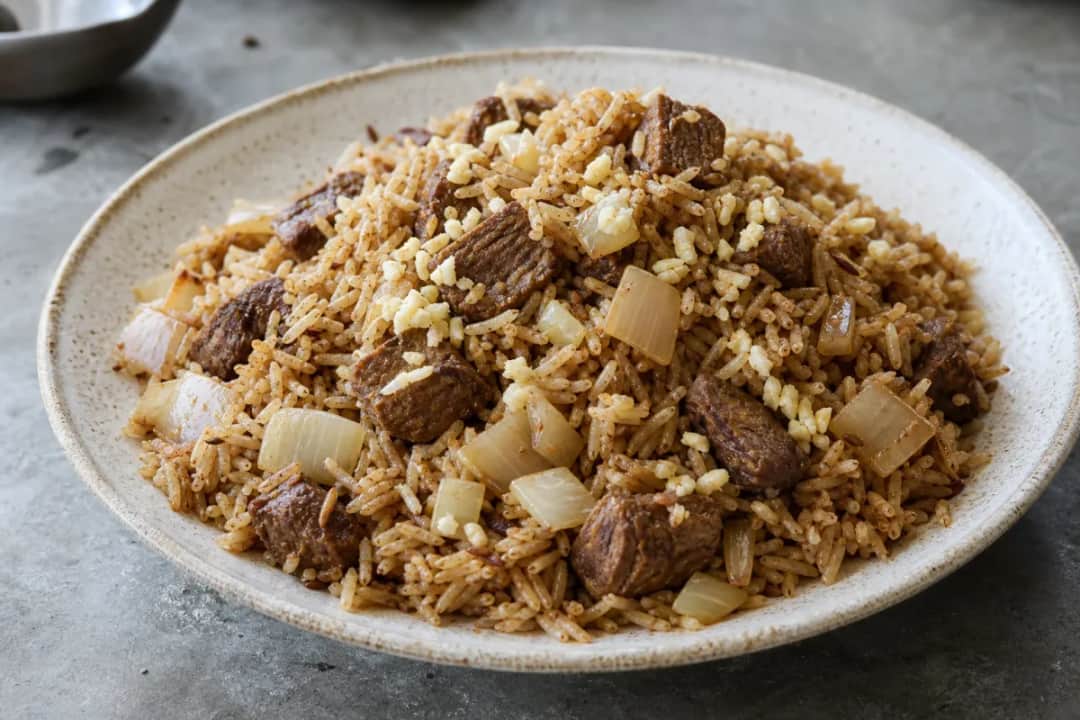 A colorful plate of Kenyan Pilau rice with beef, garnished with fresh cilantro and spices.