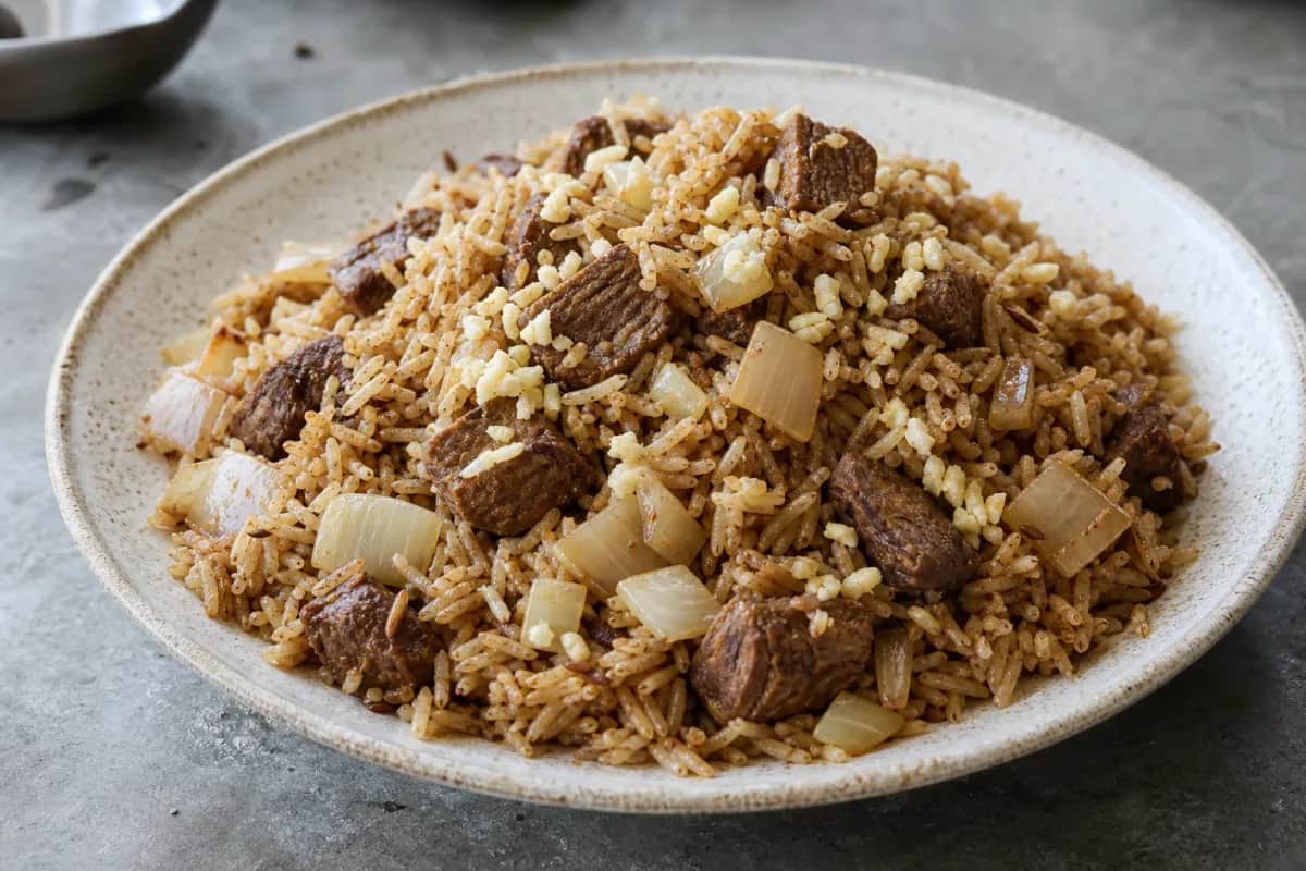 A colorful plate of Kenyan Pilau rice with beef, garnished with fresh cilantro and spices.