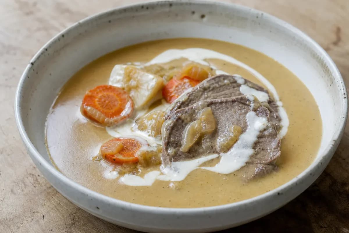 Tender beef sirloin garnished with creamy sauce, served with colorful vegetables on a plate.