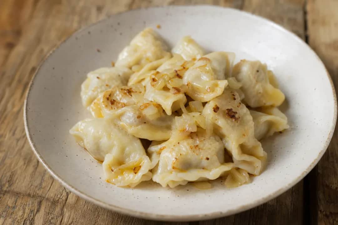 Plated Idrijski Žlikrofi dumplings garnished with herbs, showcasing the soft texture and savory filling.