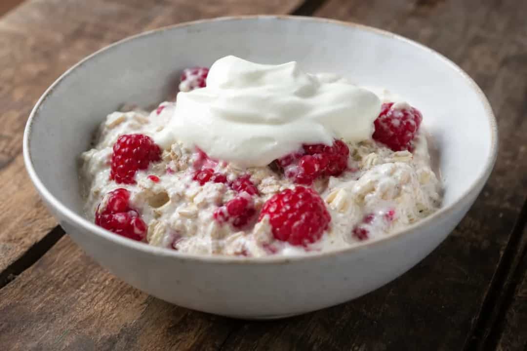 Layered dessert with raspberries, creamy texture, and oats sprinkled on top
