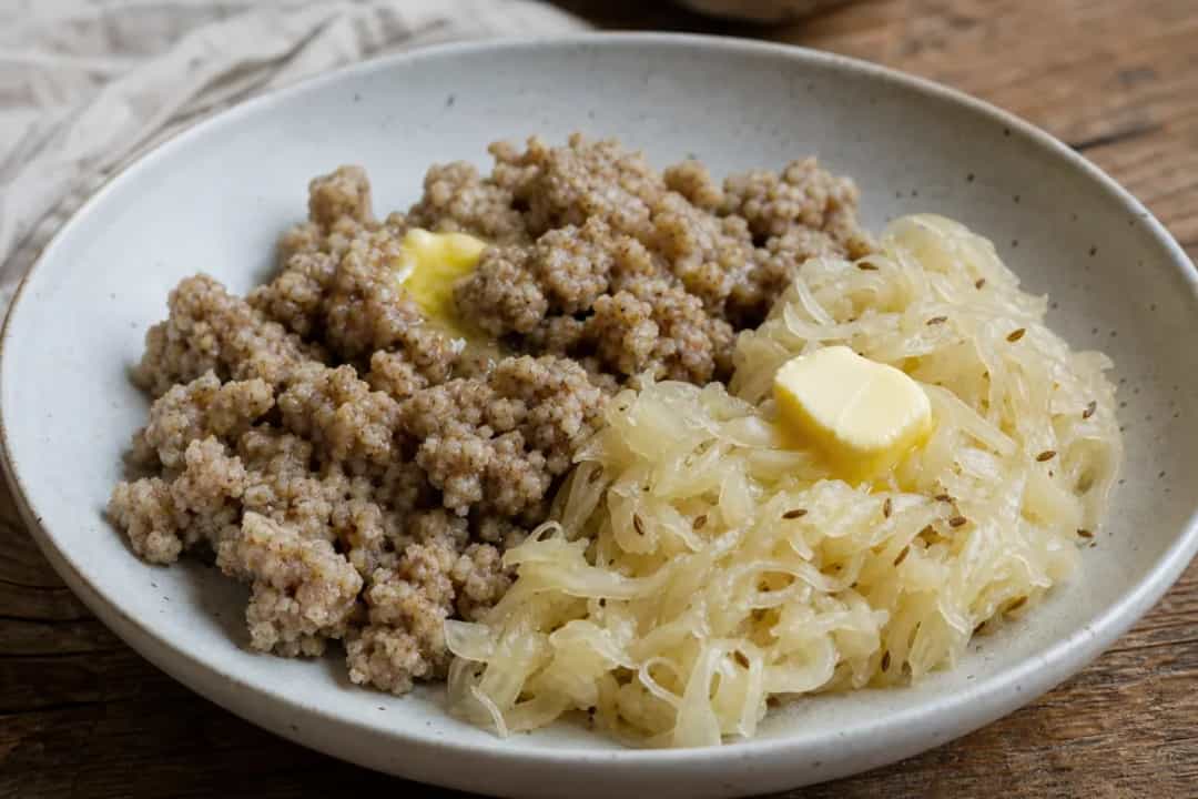 Plated buckwheat žganci with sauerkraut, showcasing rustic texture and earthy tones.