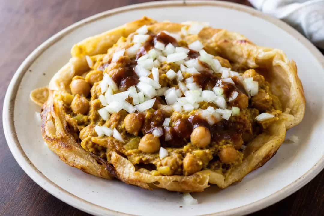 Soft golden flatbreads filled with spiced chickpeas and rich tamarind sauce, garnished with herbs.