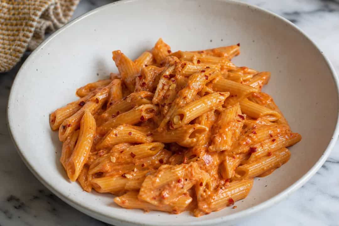 Creamy vodka pasta garnished with parmesan, chili flakes, and basil.