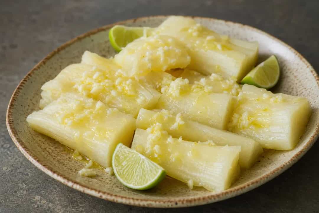 Boiled yuca served with a vibrant garlic citrus sauce and garnished with herbs.